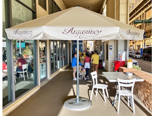 Parasol reklamowy z nadrukiem nad stolikami w kawiarni – ujęcie aranżacyjne